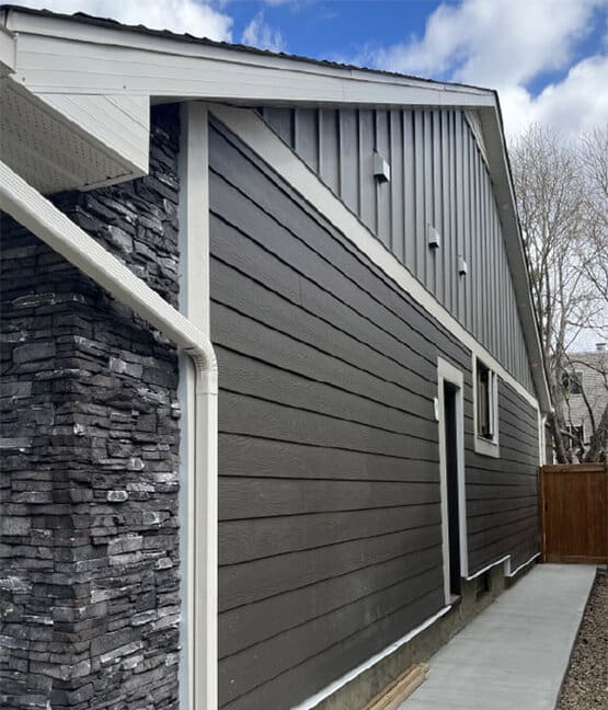 Finished home exterior with horizontal siding, vertical panel accents, and stone veneer