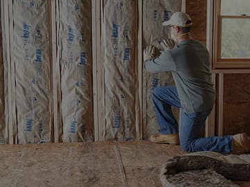 Contractor installing insulation inside a framed wall