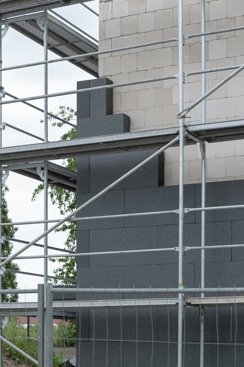 Workers install rigid exterior insulation boards on a residential building as part of an exterior insulation and energy efficiency upgrade in Edmonton.