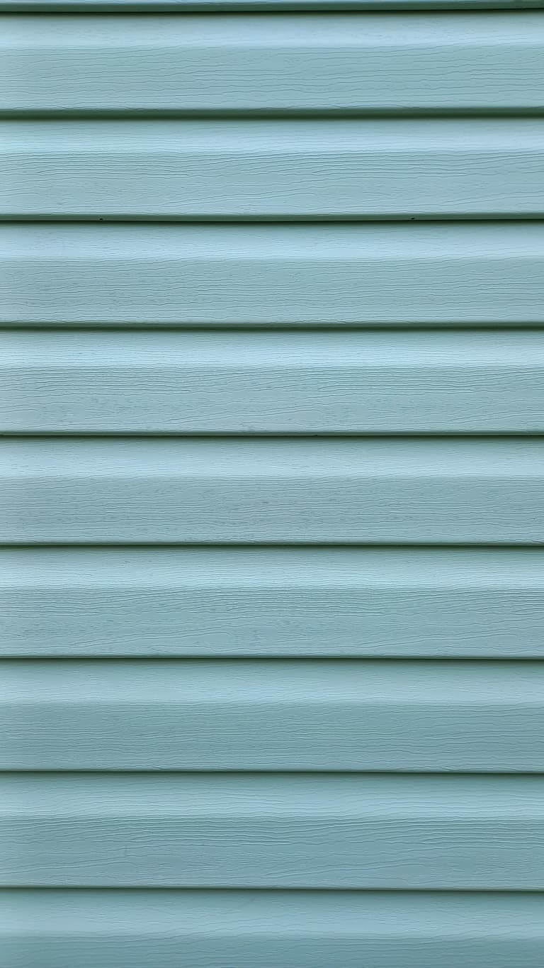 Light Blue Vinyl Siding Close-Up Close-up of light blue horizontal vinyl siding with a realistic woodgrain texture. The image showcases durable, low-maintenance exterior siding commonly used on residential homes.